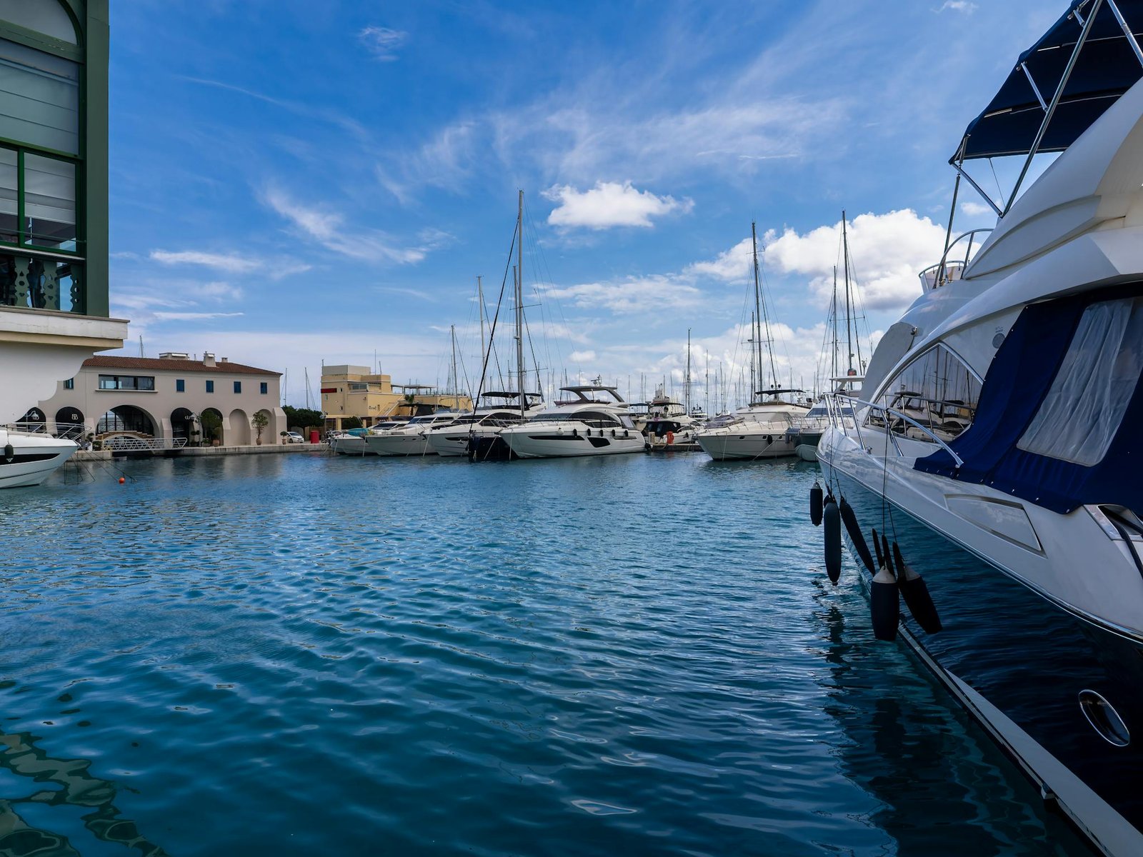 Explore the serene beauty of luxury yachts docked at a Mediterranean marina under blue skies.